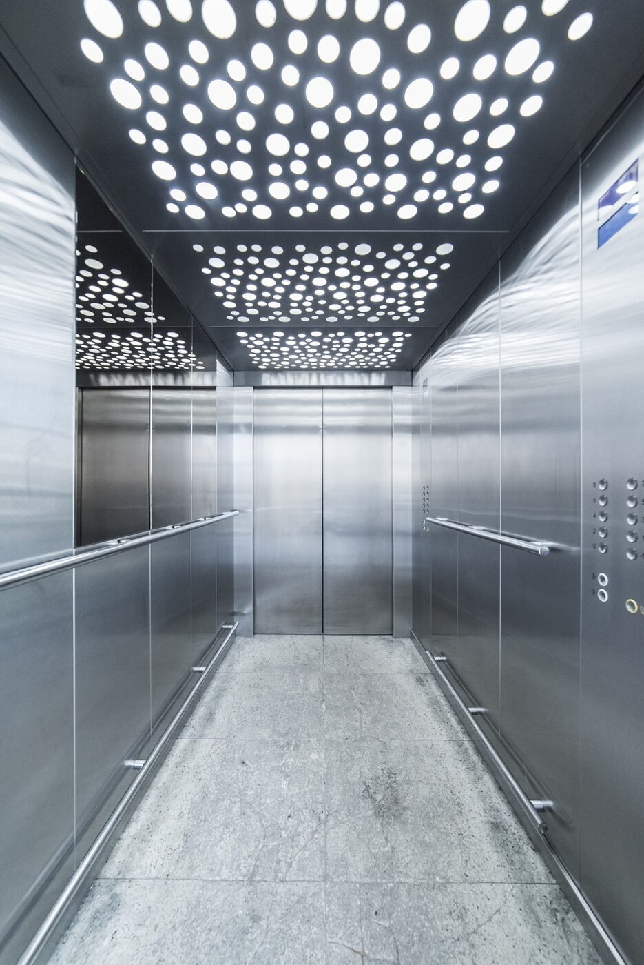 Interior de cabina de elevador em aço inox com teto iluminado